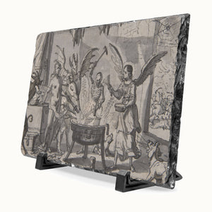 A rectangular slate art plaque featuring a monochrome gothic illustration of a scene with angels, skeletal figures, and a cauldron, displayed on a black stand against a white background.