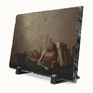 A rectangular slate sign with a still life painting print of old books, a skull, and a glass flask, displayed on a black stand against a light background.