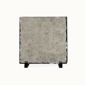 A square slate art plaque featuring an intricate, hand-carved Mayan-style calendar design, displayed on a small black stand against a white background.