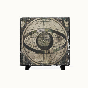 A square decorative tile or coaster featuring an antique celestial map design with the Earth at the center and orbit rings, shown on a plain white background with small black feet at the bottom.