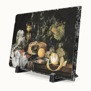 A rectangular black slate serving board with a dark still life artwork printed on it, displayed on a black stand against a light gray background.