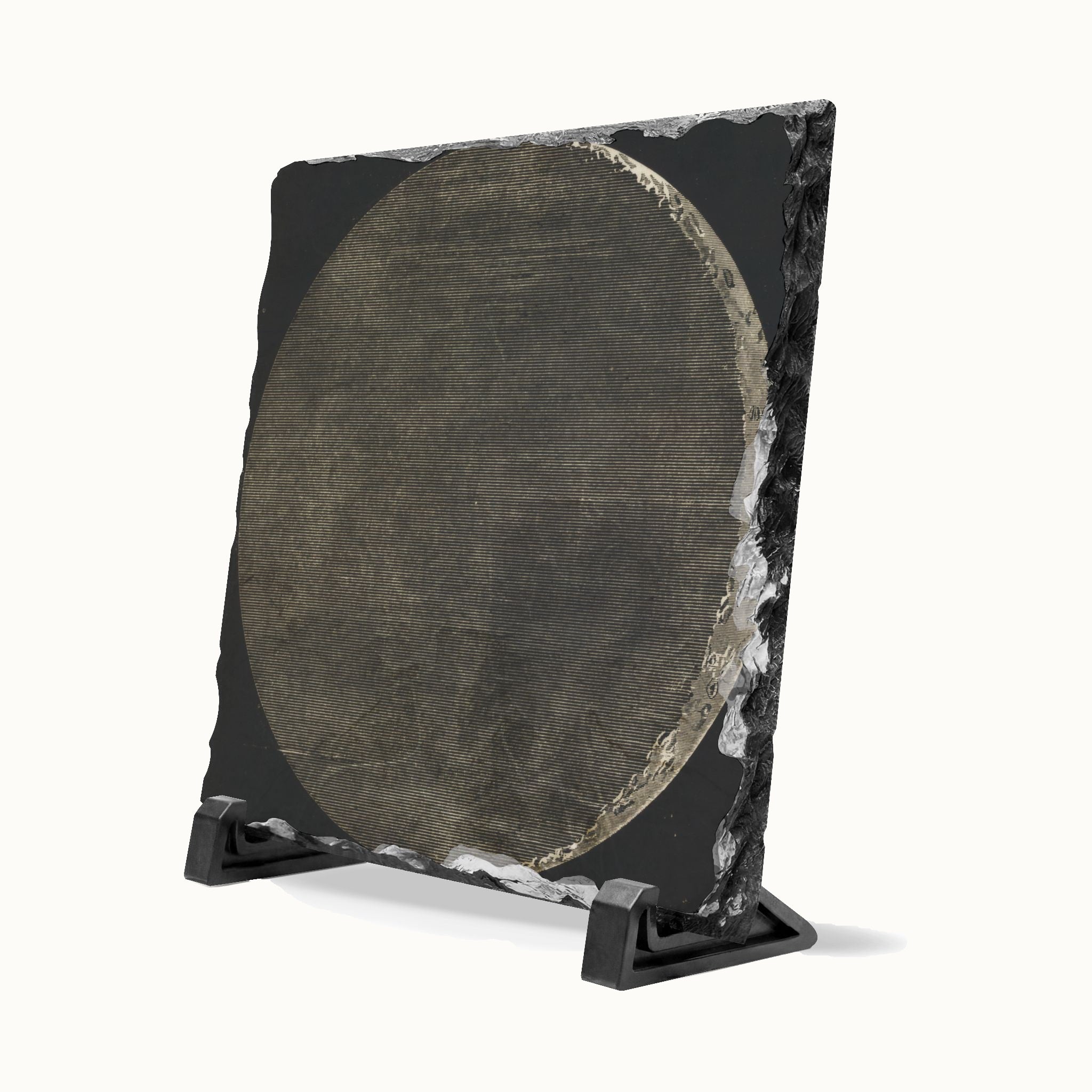 A square black stone plaque with a circular textured metallic center, displayed on a small black stand against a clean white background.