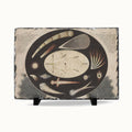 A rectangular slate serving board with a dark gray natural stone edge and a printed celestial illustration in the center, displayed on two small black stands against a light gray background.