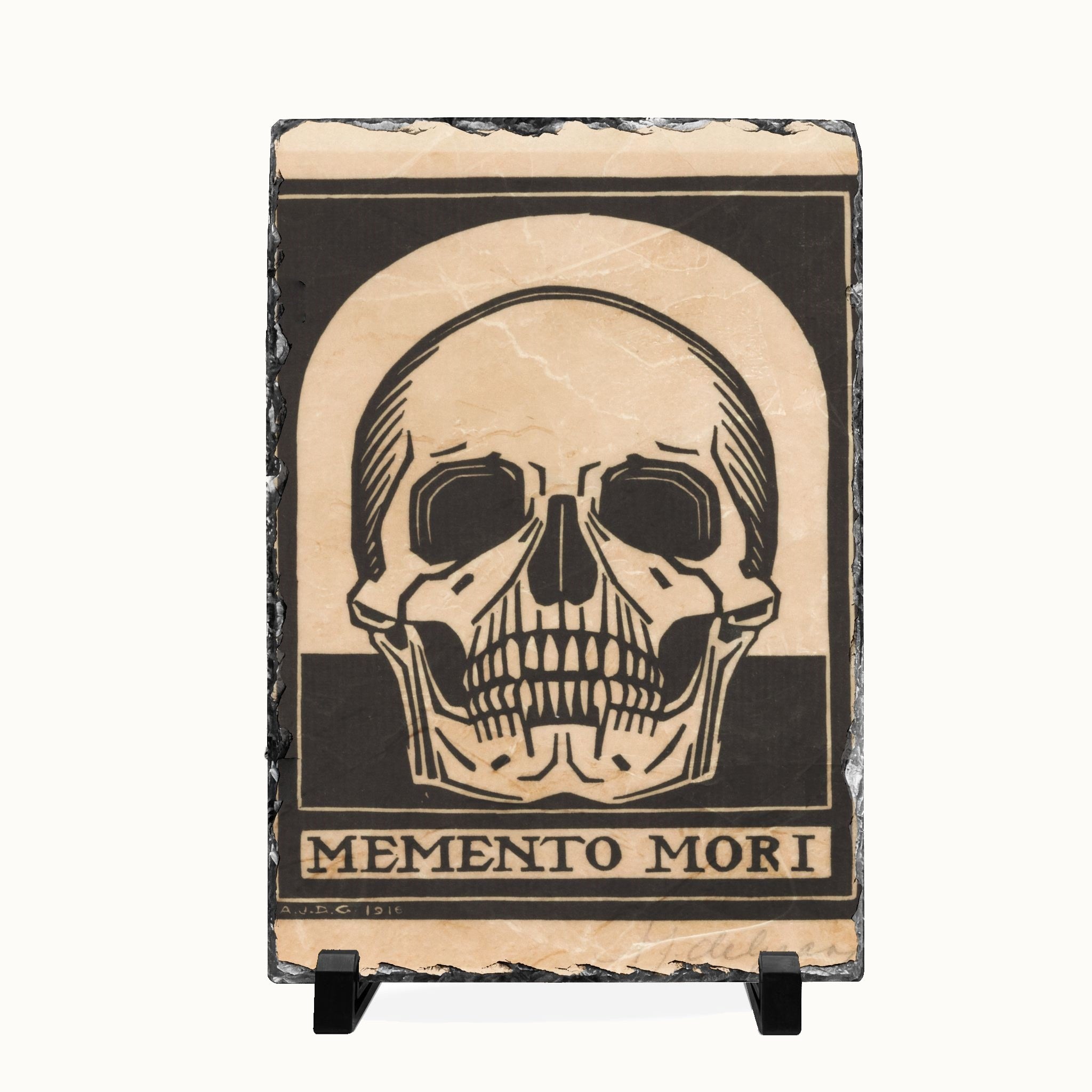 A rectangular slate sign featuring a black and beige skull graphic with the text 'MEMENTO MORI' at the bottom, displayed on a small black stand against a light background.