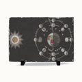 A rectangular black slate board on small black display stands, featuring a moon phase diagram and a sun illustration on a white background.