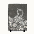 A rectangular slate sign featuring a detailed black and white illustration of a Scorpion zodiac sign, displayed on a small black stand against a light background.