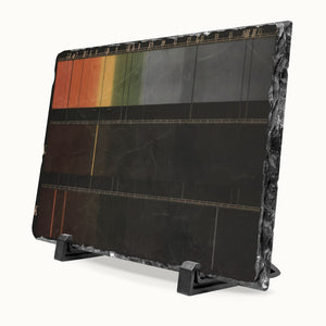 A rectangular black stone slate art plaque on a black display stand, featuring a horizontal gradient design transitioning from orange and green at the top to solid black at the bottom, with fine gold lines.