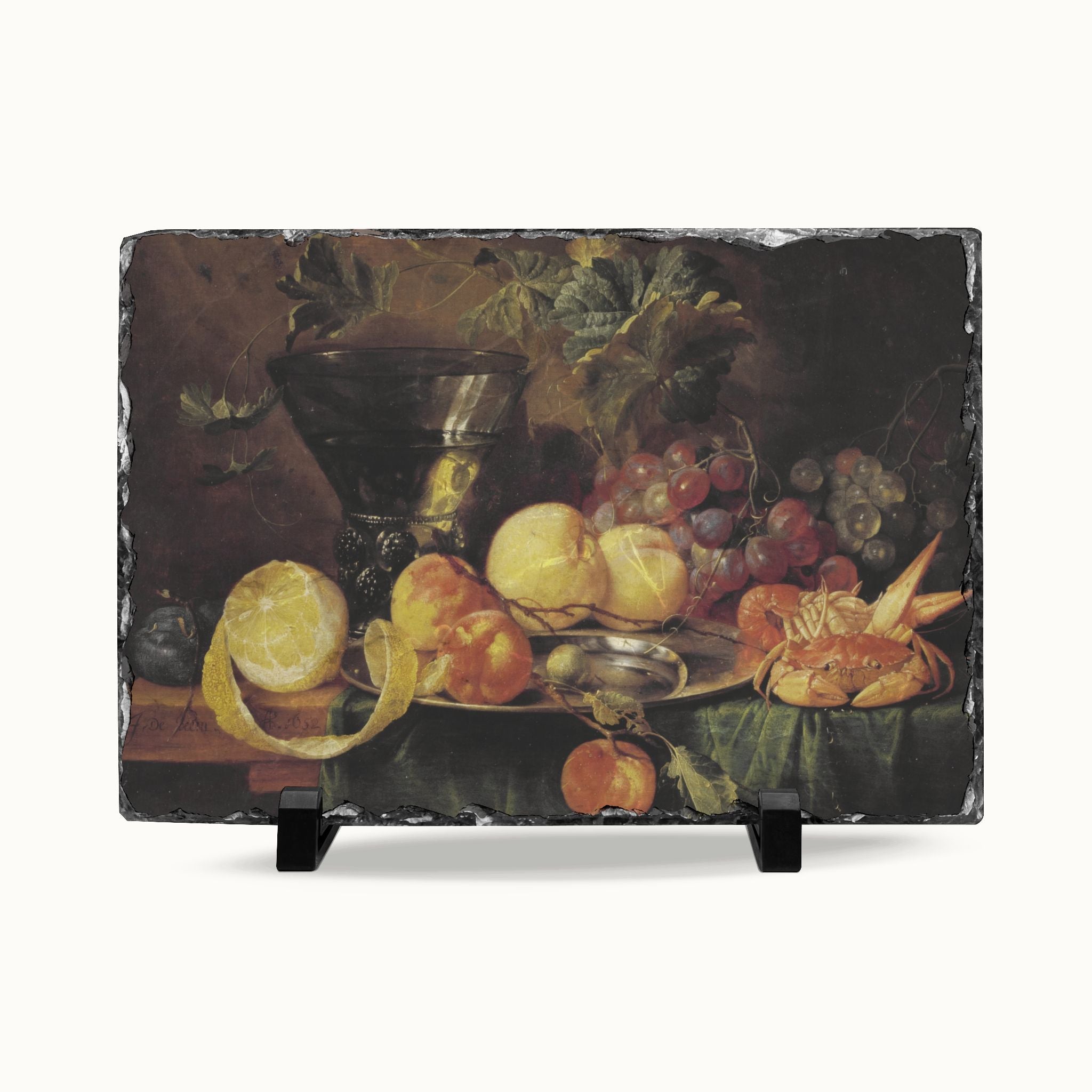 A rectangular slate serving board featuring a classic still life painting of fruit, displayed on a clean white background with two small black display stands.